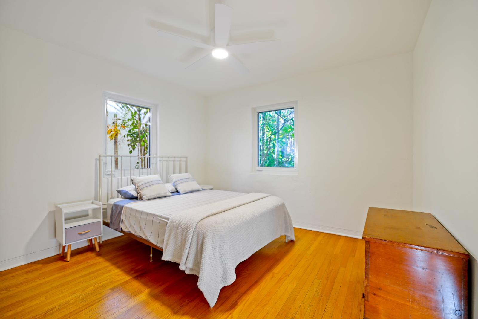 Main bedroom with hardwood floors and bright white walls