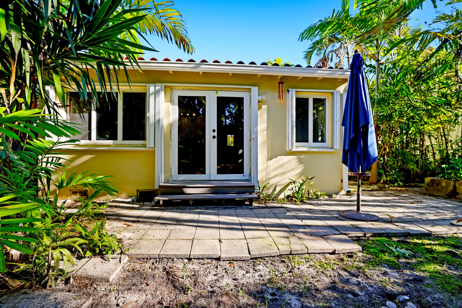 Rear exterior view showing the house framed by lush tropical landscaping